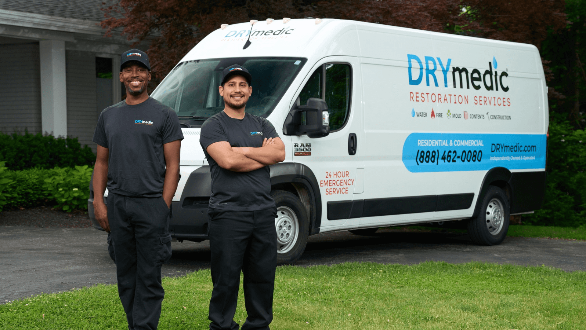 Photo of two DRYmedic team members standing in front of branded vehicle