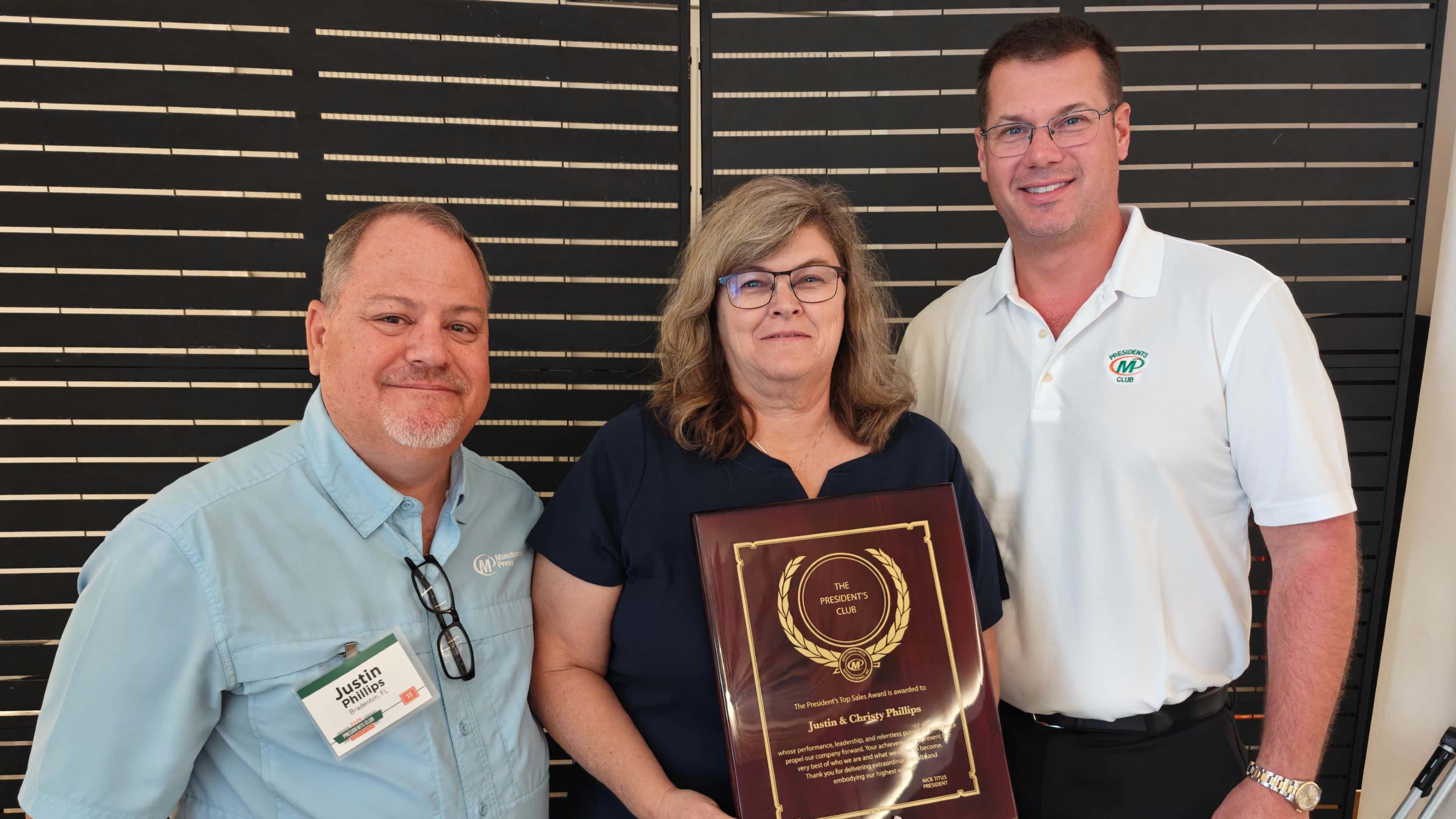 Minuteman Press Franchisees Justin & Christy Phillips accept President’s Club Award from Nick Titus.