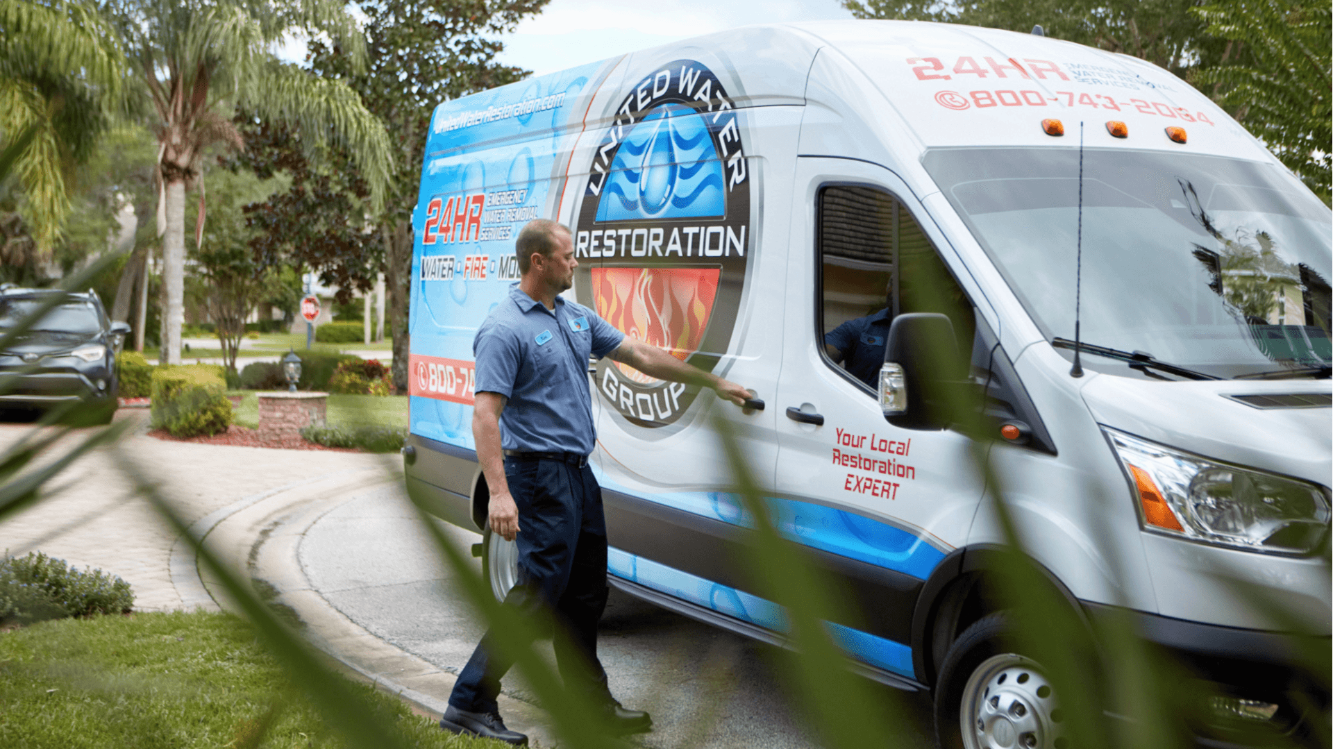 Photo of United Water Restoration Group team member walking up to service vehicle