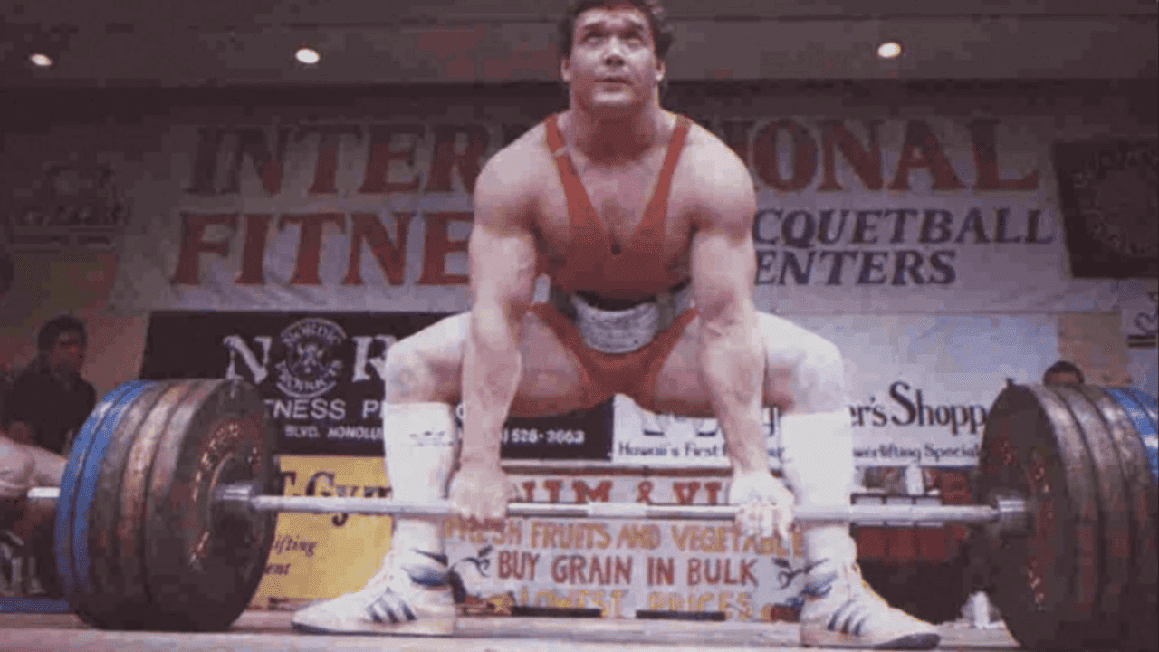 How undefined Evolved and Set New Standards Photo of powerlifter, wearing red singlet and white socks, preparing to deadlift