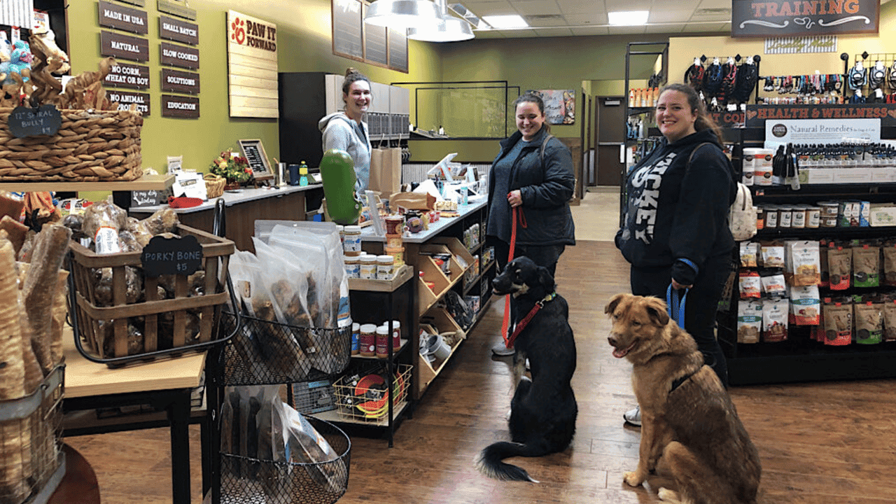 How Franchisees Are Building Local Impact and Creating Jobs in Their Communities Photo of two customers, with two dogs, and an employee in a Pet Wants location