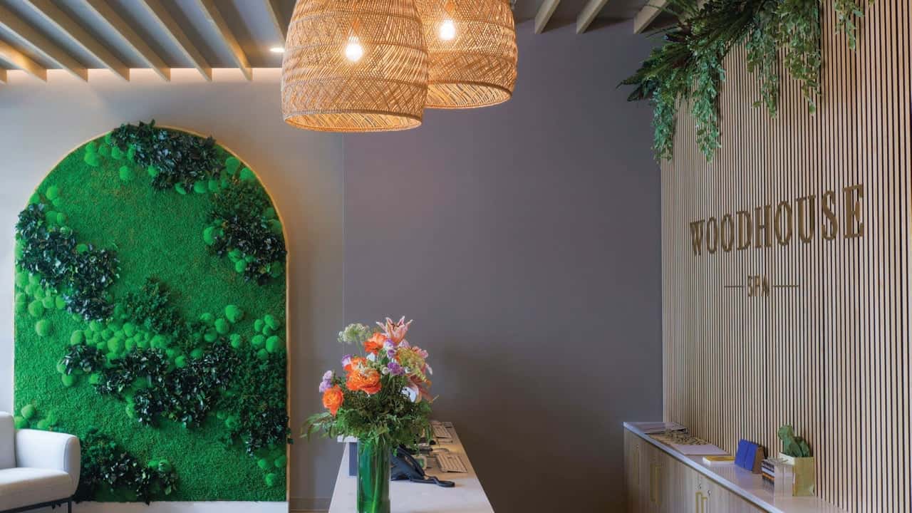 How undefined Evolved and Set New Standards photo of Woodhouse Spa front desk with flowers, greenery, and pendant lights