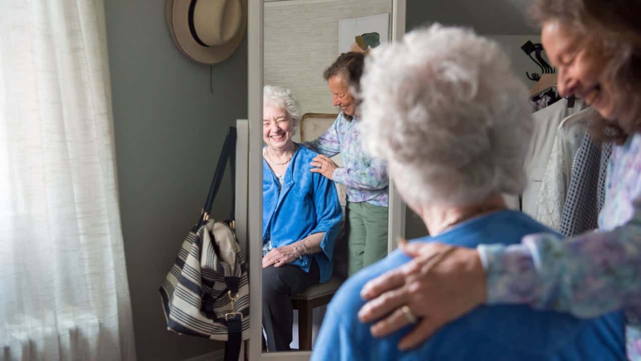Seniors Helping Seniors® In-Home Care Services Expands Photo of two seniors looking into full-body mirror, smiling