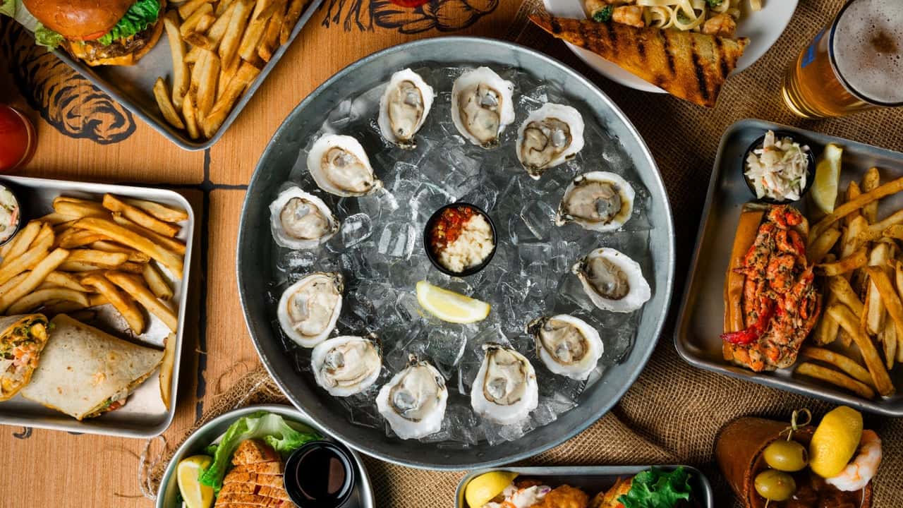 Shuckin’ Shack Eyes Greenville, North Carolina Photo of spread of Shuckin' Shack menu items on table featuring oysters in the middle