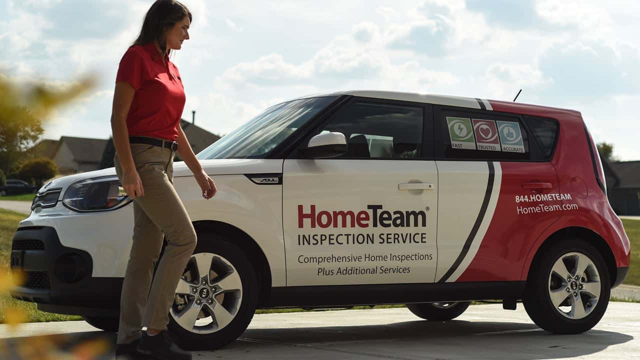 Real Estate Today: Behind the Drywall: The Truth About Home Photo of HomeTeam inspector in red polo and khaki pants, walking by branded vehicle
