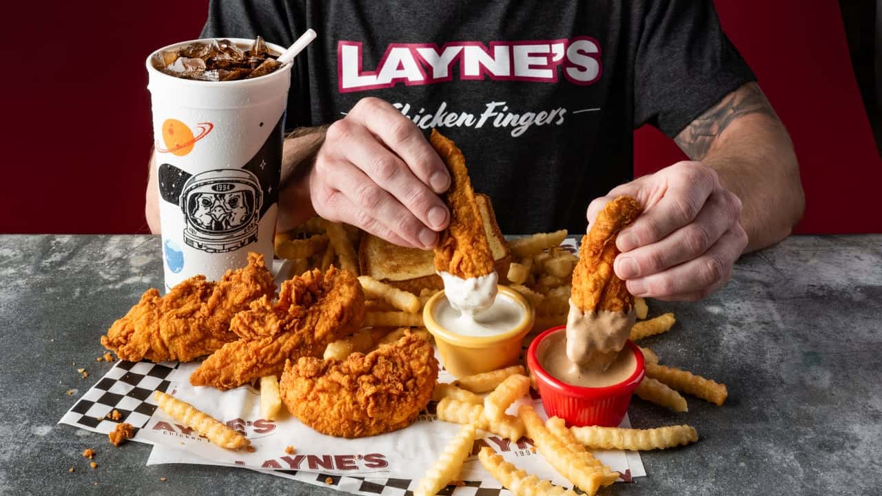 Why Layne’s Chicken Fingers Shines as the Real Chicken Photo of person dipping Layne's Chicken Fingers in sauce