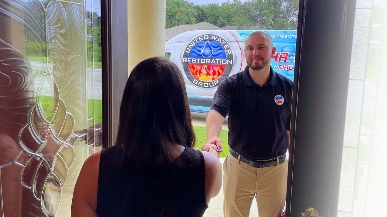 How United Water Restoration Group Evolved and Set New Standards Photo of UWRG team member shaking homeowner's hand